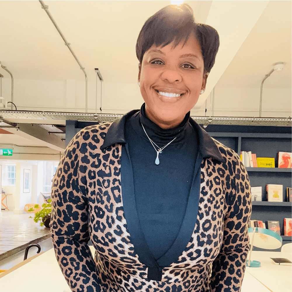 Smiling woman wearing a leopard print cardigan and black turtleneck.