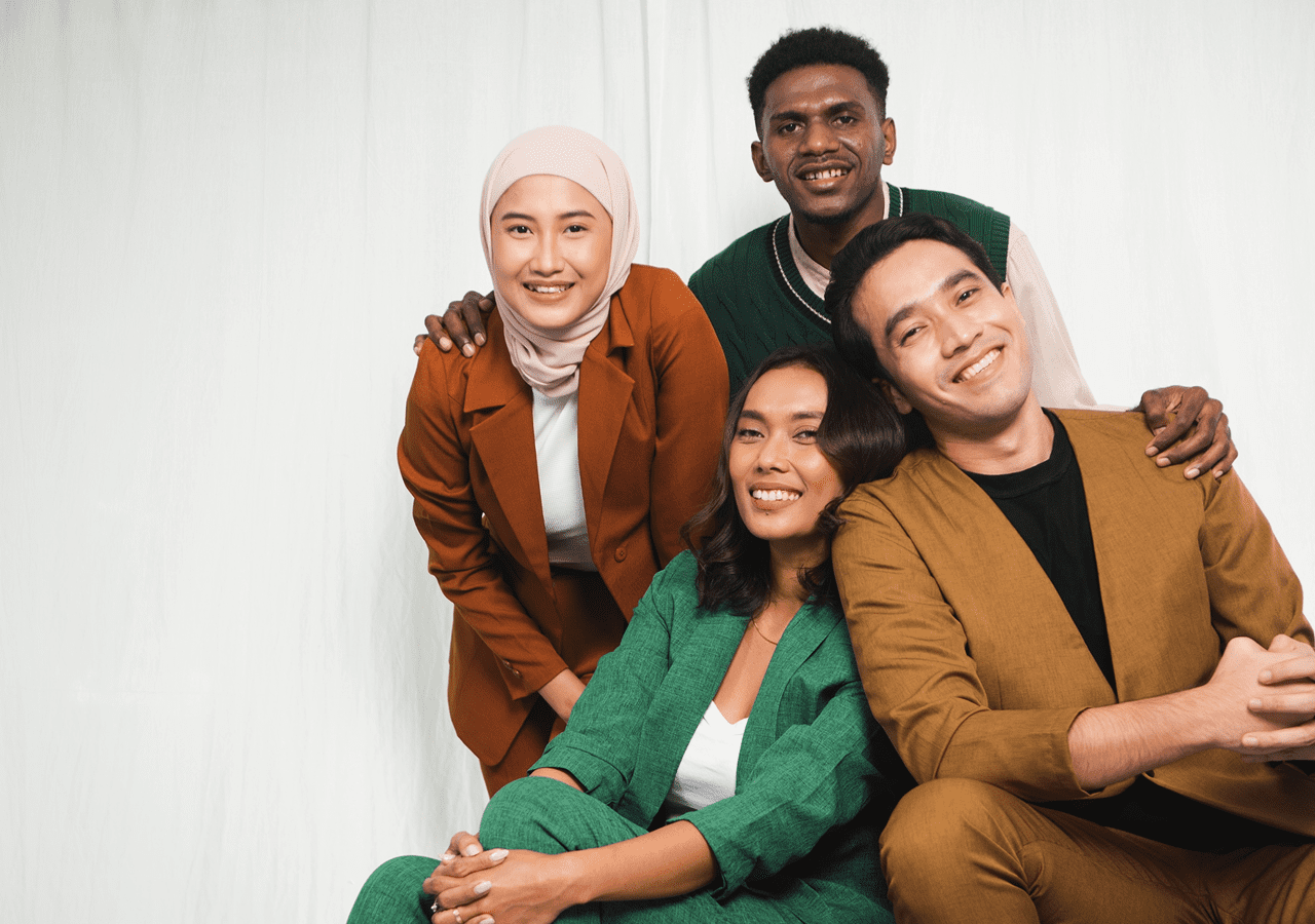 A diverse group of four friends smiling and posing together against a white background.