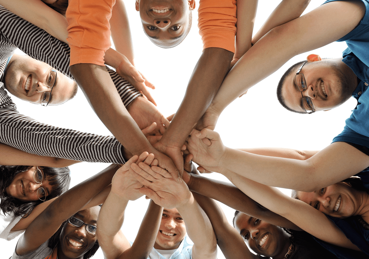 Group of diverse people stacking hands in unity and teamwork.