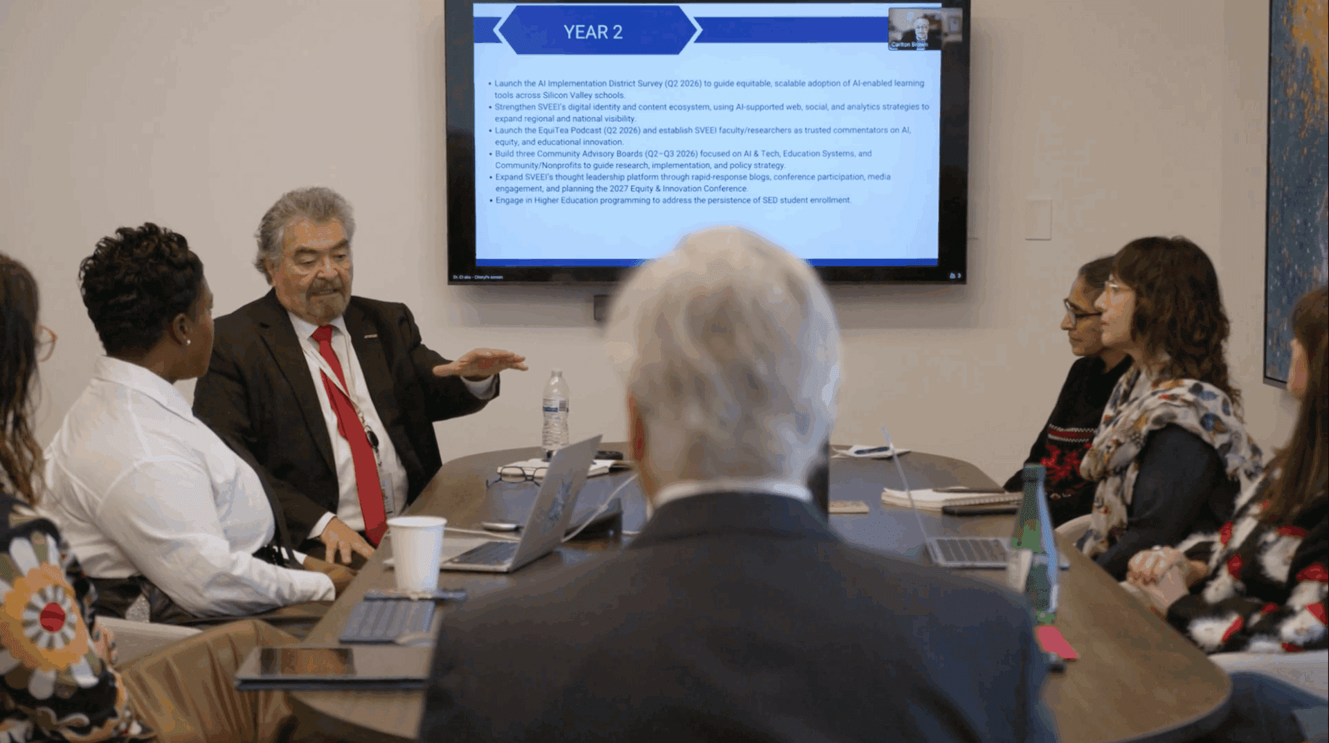 Business meeting with a man presenting information on a screen.